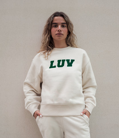 Woman wearing the Freshman Sweatshirt in Natural with forest green LUV graphic